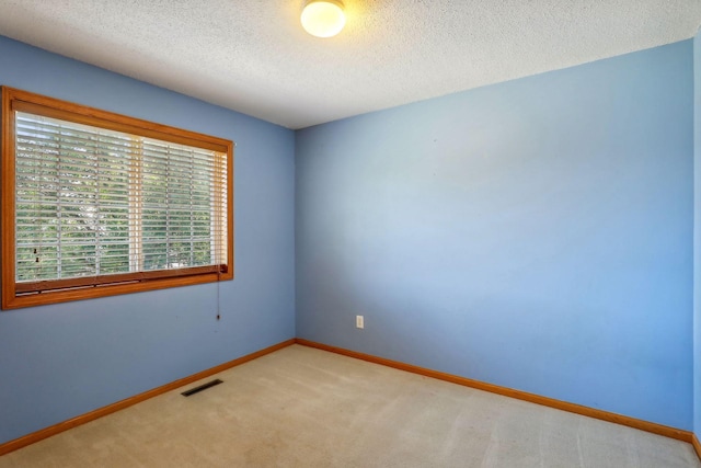 empty room with a textured ceiling and light colored carpet