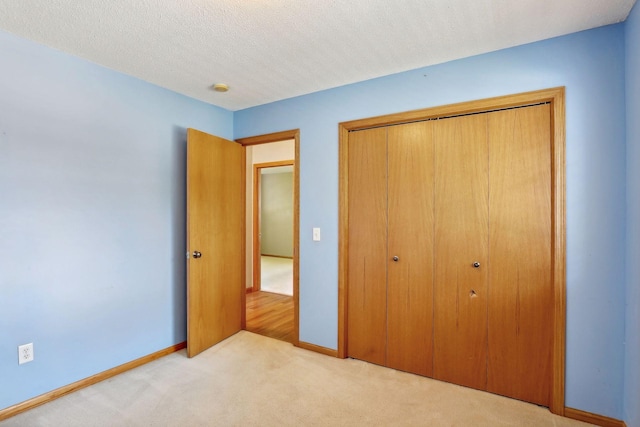 unfurnished bedroom with a textured ceiling, a closet, and light carpet