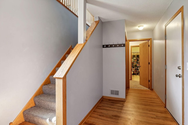 stairway with hardwood / wood-style floors and a textured ceiling