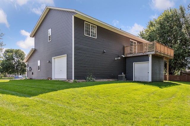 rear view of house featuring a garage, a lawn, and central AC