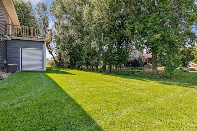 view of yard with a garage, central AC, and a trampoline