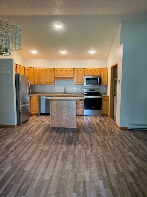 kitchen with dark wood-type flooring, stainless steel appliances, sink, and vaulted ceiling