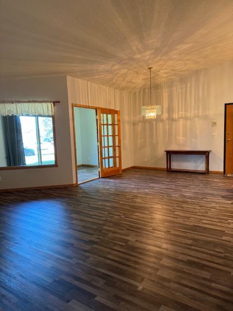 unfurnished room featuring dark hardwood / wood-style floors, an inviting chandelier, and french doors