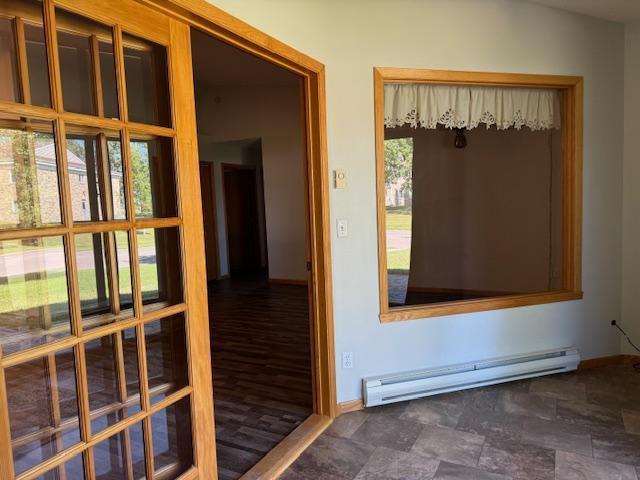 doorway to outside featuring baseboard heating and a healthy amount of sunlight