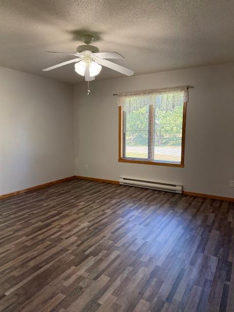 unfurnished room with baseboard heating, dark wood-type flooring, and a textured ceiling