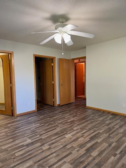 unfurnished bedroom with dark hardwood / wood-style flooring, ceiling fan, and a textured ceiling