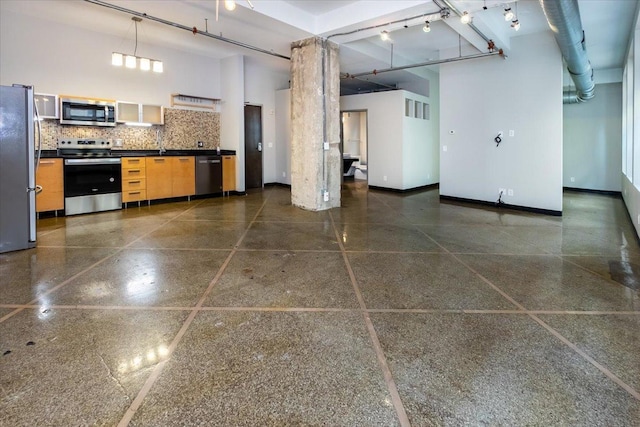 kitchen with track lighting, stainless steel appliances, and a towering ceiling