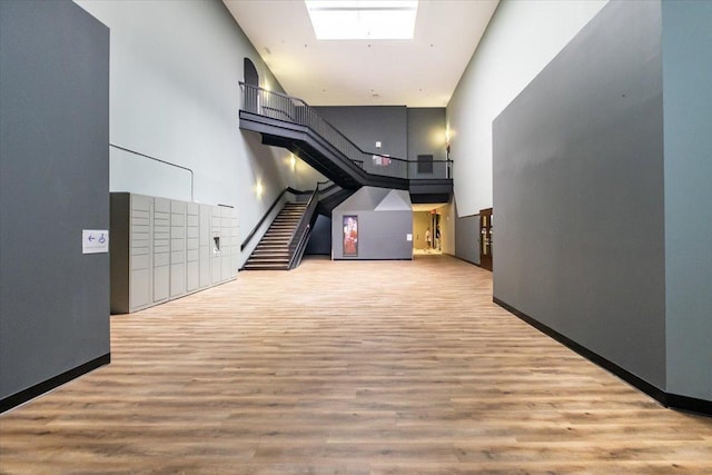 corridor featuring a skylight, wood-type flooring, and a towering ceiling