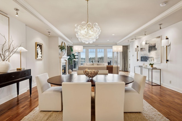 dining area with wood-type flooring, ornamental molding, and a notable chandelier