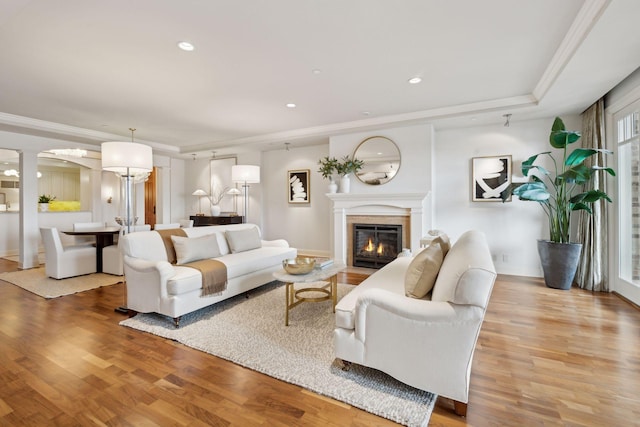 living room with ornate columns, ornamental molding, and light wood-type flooring