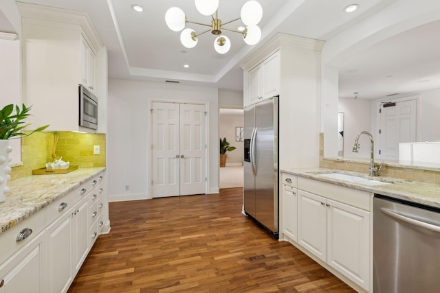 kitchen with sink, appliances with stainless steel finishes, white cabinetry, light stone countertops, and a raised ceiling