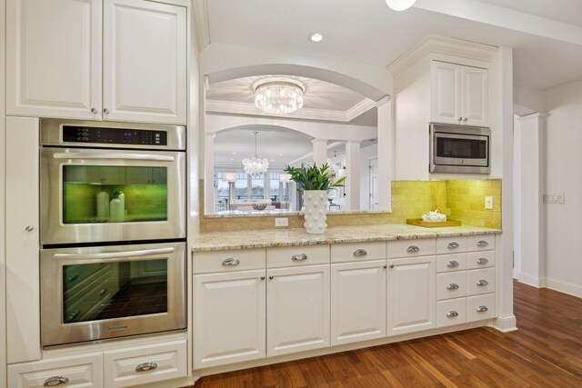 kitchen featuring white cabinetry, appliances with stainless steel finishes, dark hardwood / wood-style floors, light stone countertops, and decorative backsplash