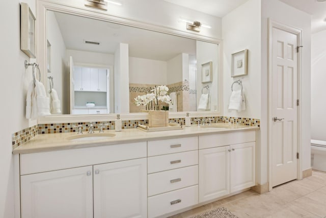 bathroom featuring tile patterned floors, vanity, toilet, and backsplash