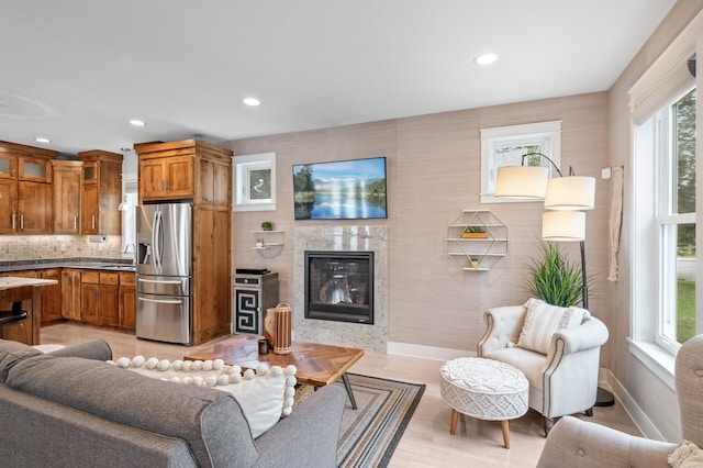 living room featuring sink, light hardwood / wood-style flooring, and a premium fireplace