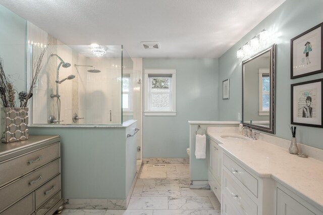 bathroom with tiled shower, a textured ceiling, vanity, and toilet