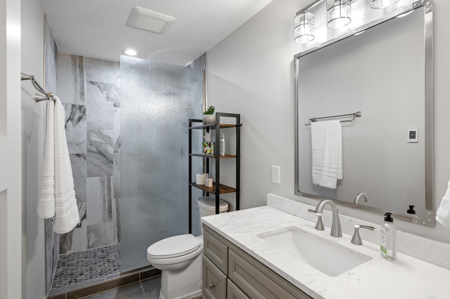 bathroom featuring a tile shower, vanity, toilet, and tile patterned floors