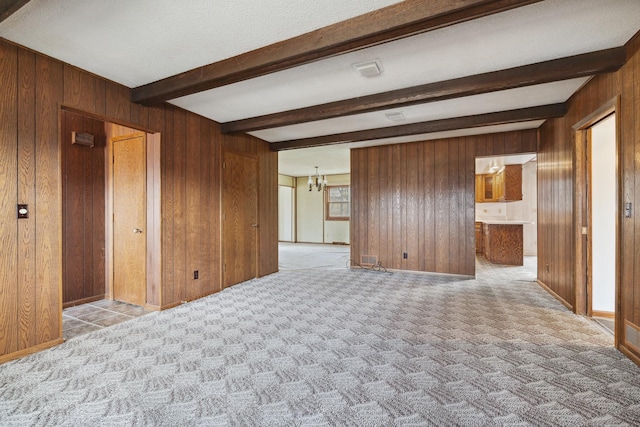 spare room featuring wood walls, beamed ceiling, light carpet, and an inviting chandelier