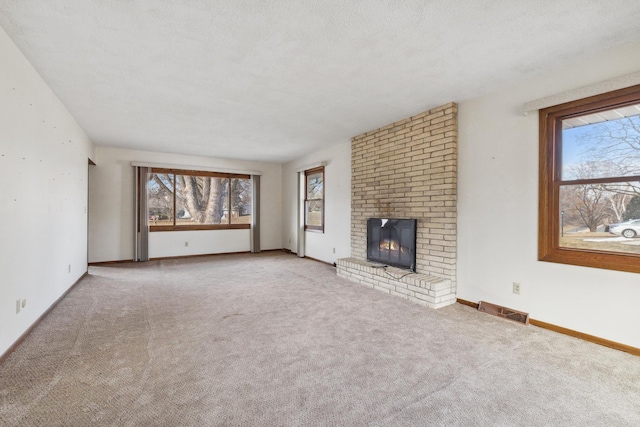 unfurnished living room with light colored carpet, a textured ceiling, and a brick fireplace