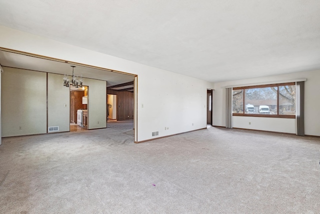 unfurnished living room featuring light carpet and a chandelier