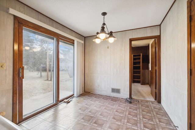 unfurnished room with wood walls and a chandelier