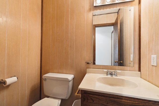 bathroom with wooden walls, vanity, and toilet