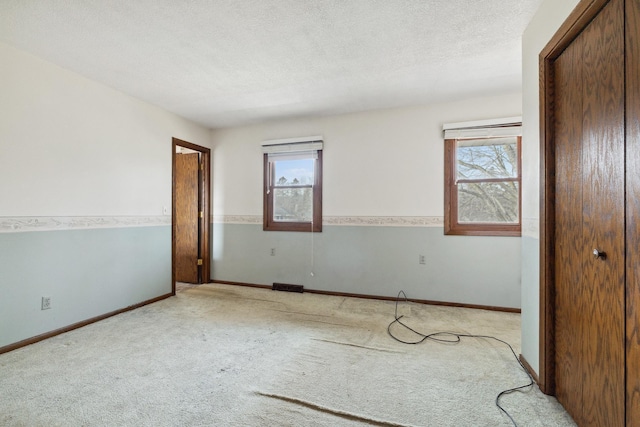 unfurnished bedroom featuring a textured ceiling and light carpet