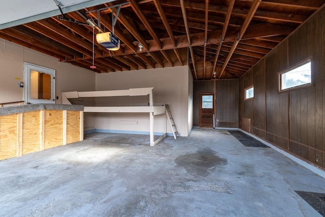 garage featuring a garage door opener and wooden walls