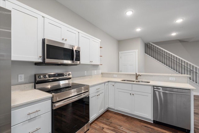 kitchen with kitchen peninsula, dark hardwood / wood-style floors, stainless steel appliances, and white cabinets