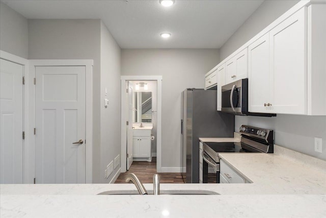 kitchen featuring dark hardwood / wood-style floors, sink, white cabinetry, appliances with stainless steel finishes, and light stone countertops