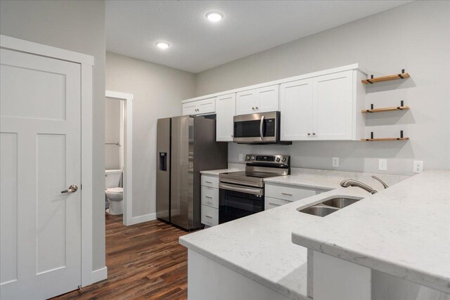 kitchen with sink, dark wood-type flooring, white cabinetry, appliances with stainless steel finishes, and light stone countertops