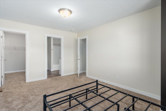 carpeted bedroom with a textured ceiling, a walk in closet, and a closet