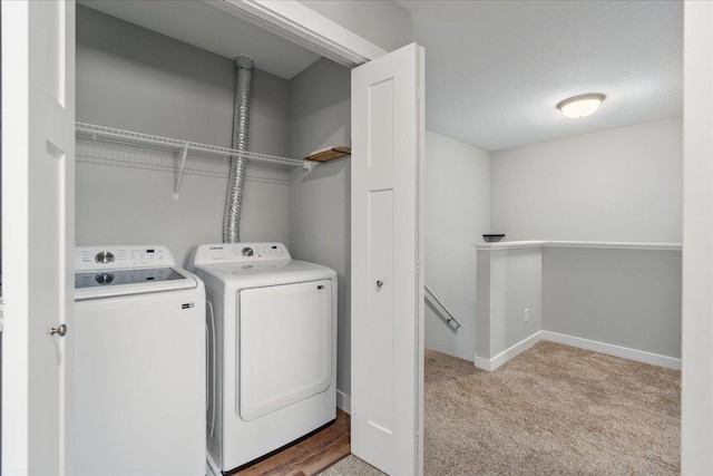 clothes washing area with a textured ceiling, washer and clothes dryer, and light colored carpet