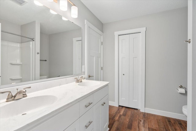 bathroom with a shower, vanity, a textured ceiling, toilet, and hardwood / wood-style floors