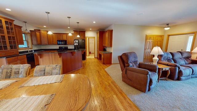 kitchen featuring a kitchen bar, dark countertops, glass insert cabinets, open floor plan, and black appliances