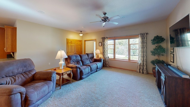 living room with baseboards, a ceiling fan, and light colored carpet