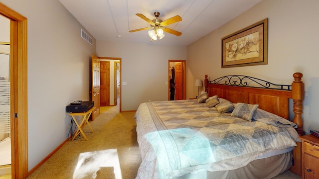 bedroom featuring light colored carpet, a walk in closet, visible vents, and baseboards