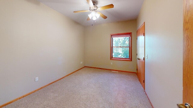 unfurnished room featuring light carpet, a ceiling fan, and baseboards