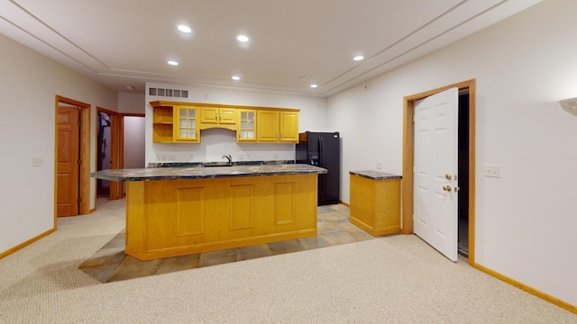 kitchen featuring light carpet, visible vents, black fridge with ice dispenser, dark countertops, and a kitchen island with sink