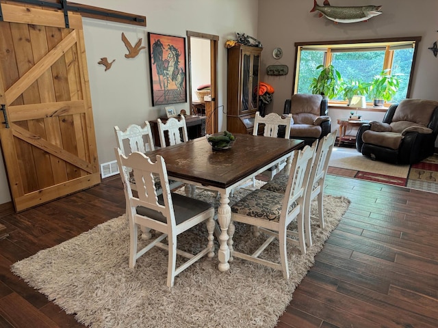 dining room featuring a barn door, visible vents, and hardwood / wood-style floors