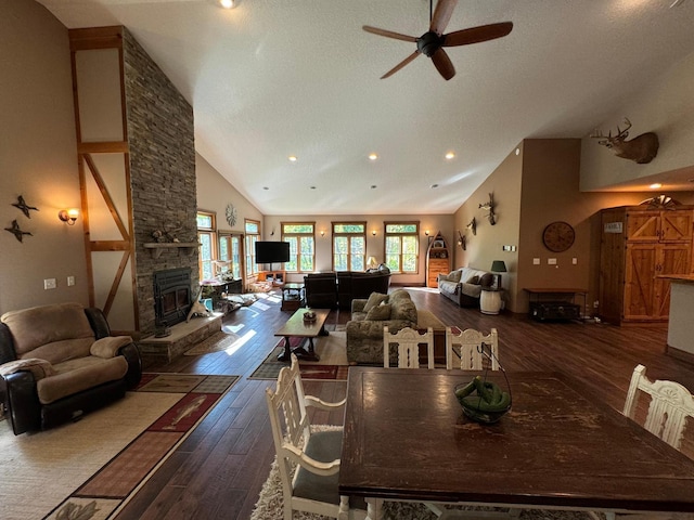 dining room featuring a ceiling fan, wood finished floors, high vaulted ceiling, a fireplace, and a textured ceiling