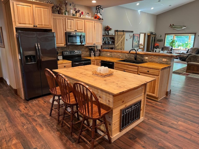 kitchen with black appliances, a sink, a barn door, a peninsula, and wooden counters