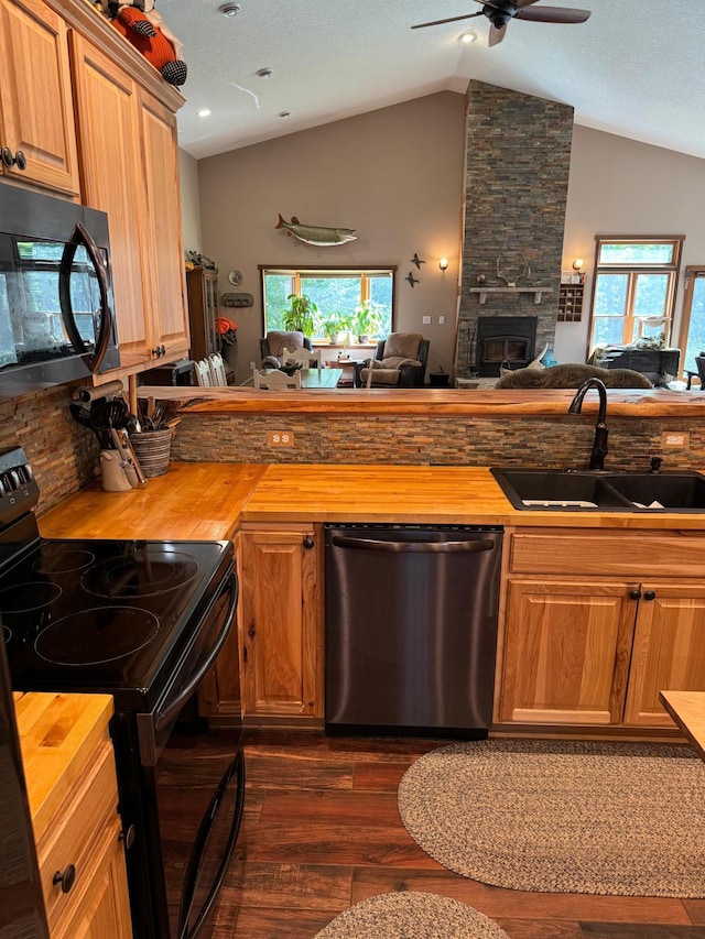 kitchen with a sink, wooden counters, black appliances, and open floor plan