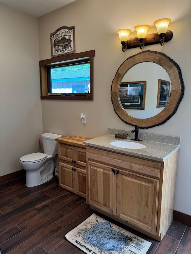 half bath featuring toilet, vanity, baseboards, and wood finished floors