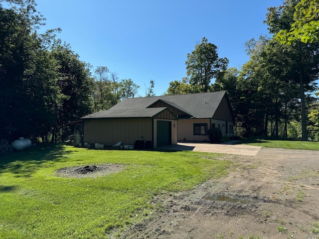 view of front of house featuring an attached garage, a front lawn, board and batten siding, and driveway