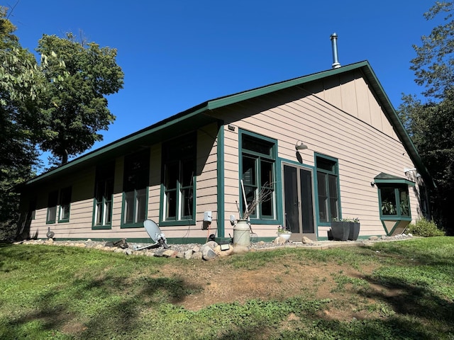 back of property featuring board and batten siding and a yard