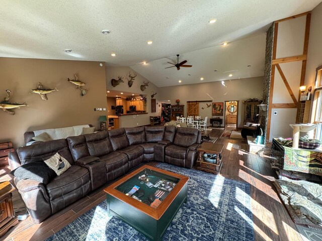 living area with wood finish floors, lofted ceiling, a textured ceiling, and ceiling fan