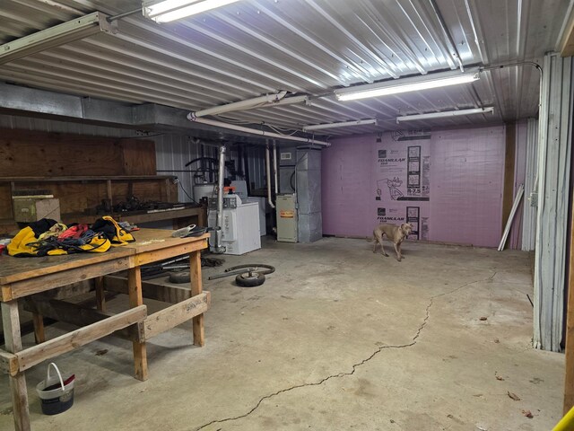 unfinished basement featuring heating unit, a workshop area, and washer / clothes dryer