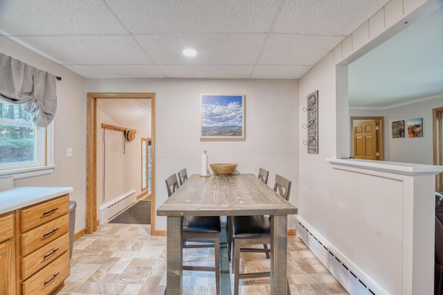 dining area featuring a drop ceiling, a baseboard heating unit, and baseboards