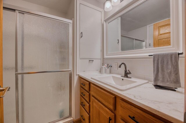 bathroom with vanity, an enclosed shower, and tasteful backsplash