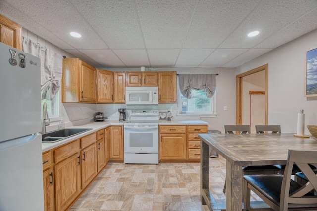 kitchen featuring a sink, light countertops, white appliances, and stone finish flooring